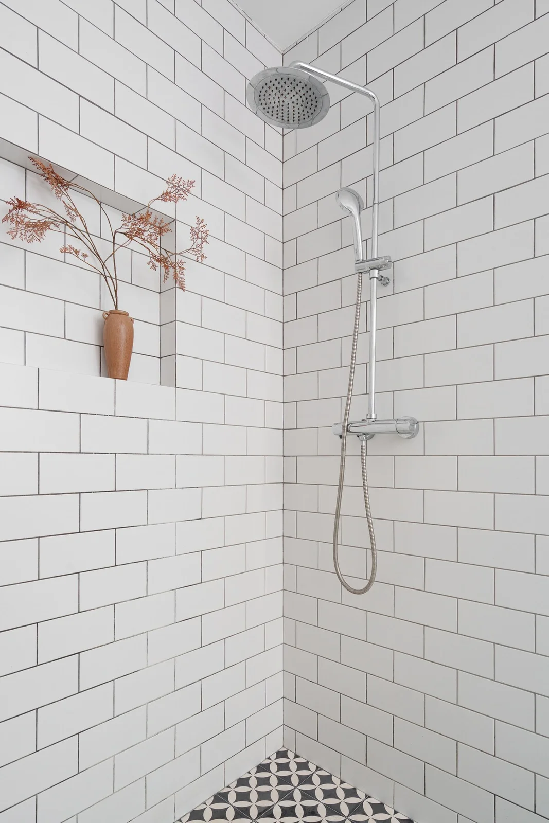 Walk-in shower detail with terracotta vase tucked into a tiled niche