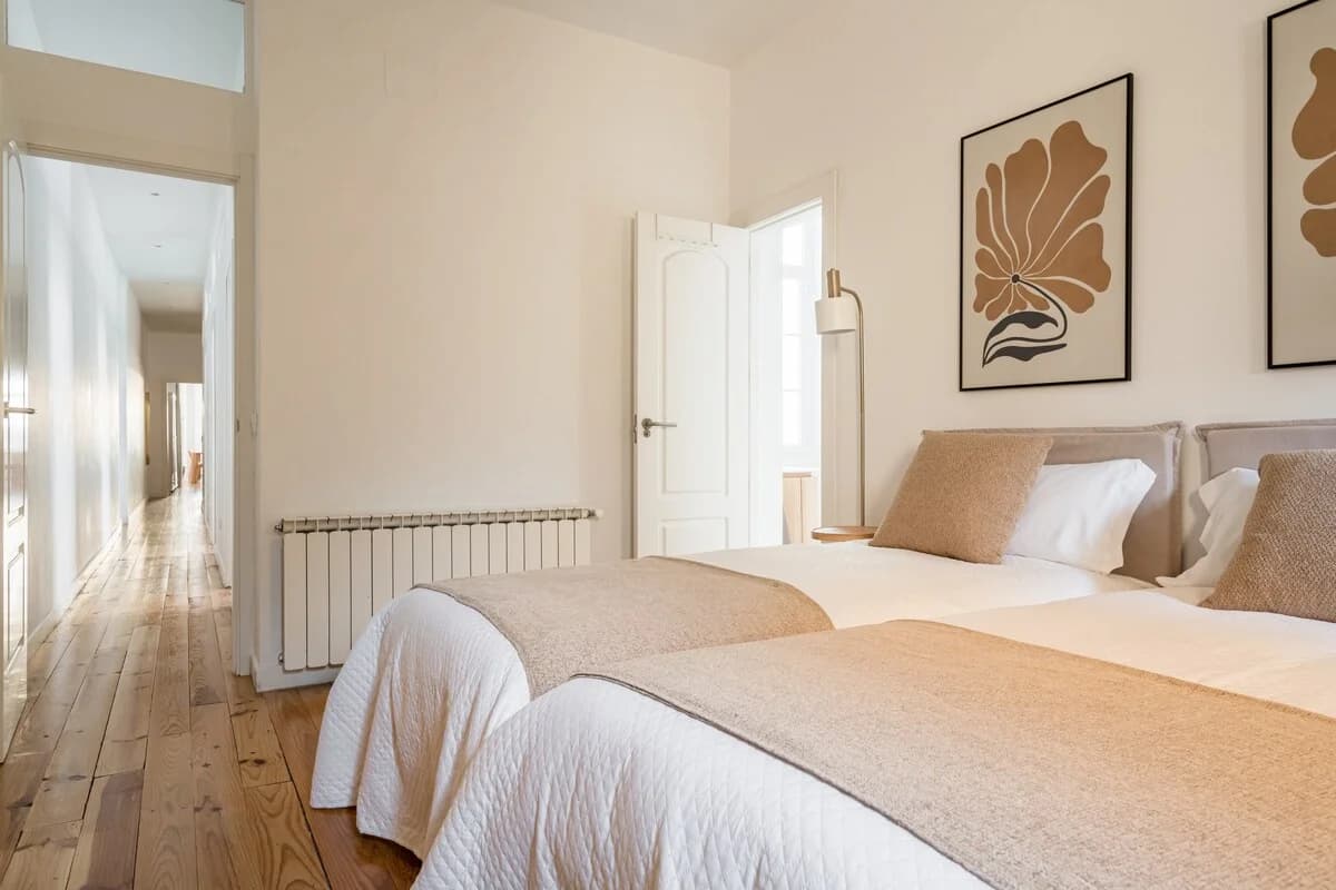 Twin bedroom with botanical prints, brass lamp and view down the hallway