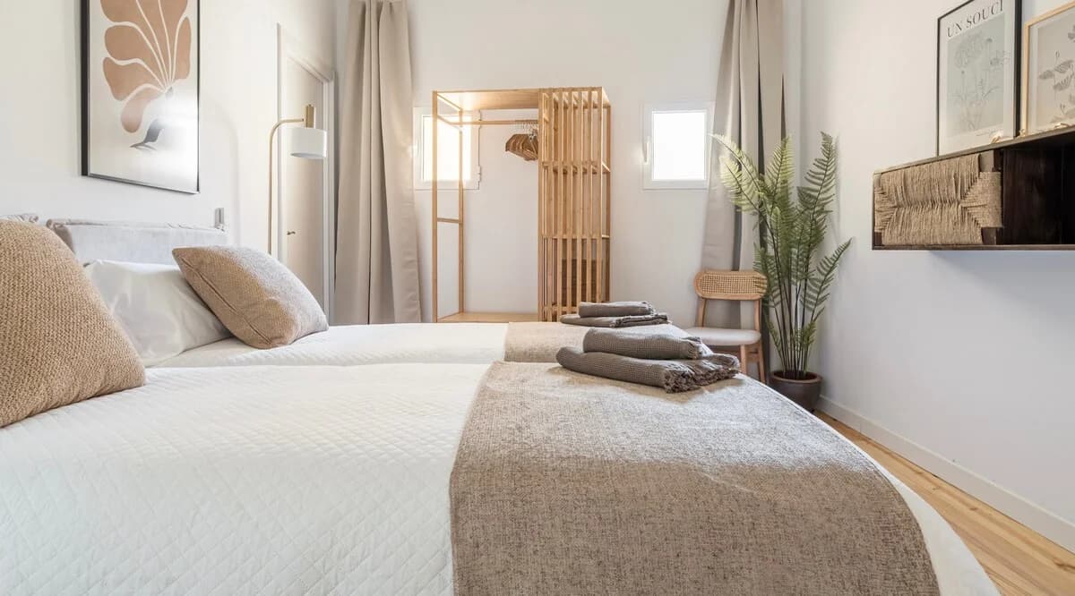 Calm twin bedroom in oat tones with slatted wood wardrobe and fern