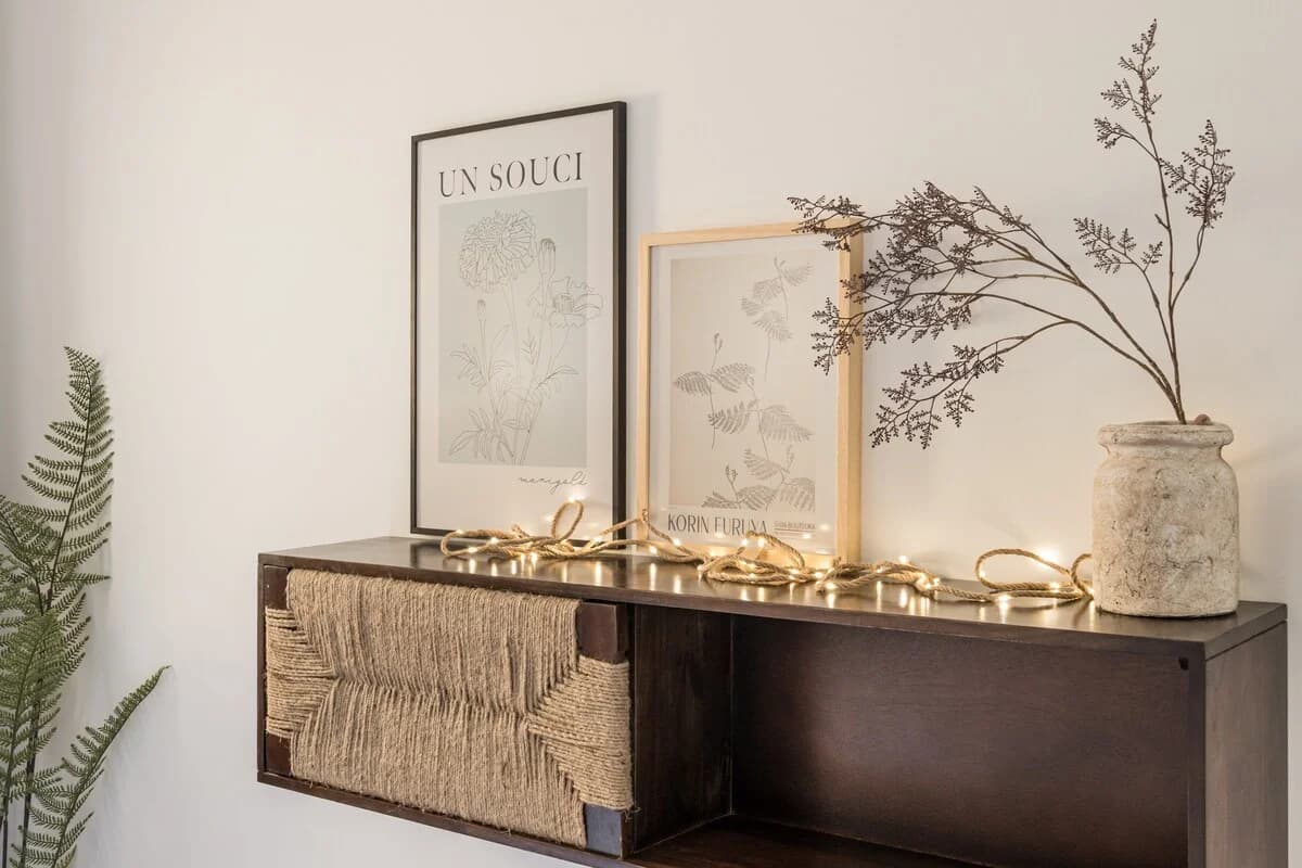 Console vignette with framed botanical prints and rope-light glow