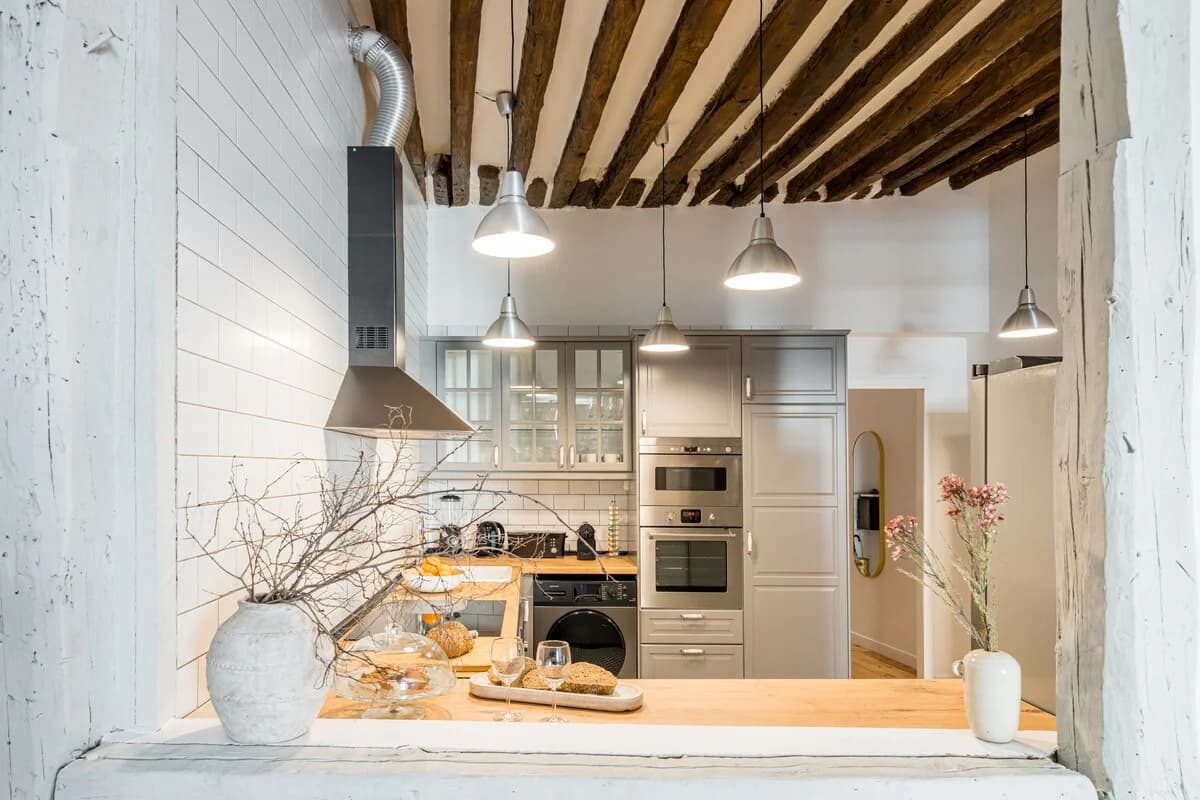Beam-ceilinged kitchen with industrial pendants and original timber framing
