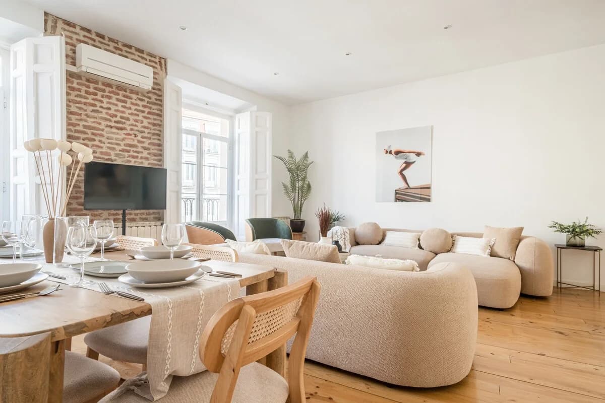 Living room from dining table with curving bouclé sofa and brick wall