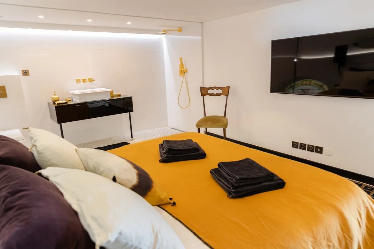 Compact suite bedroom with brass shower wall and saffron throw