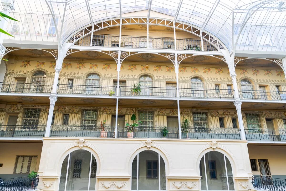 Belle Epoque interior courtyard with painted balconies under glass canopy