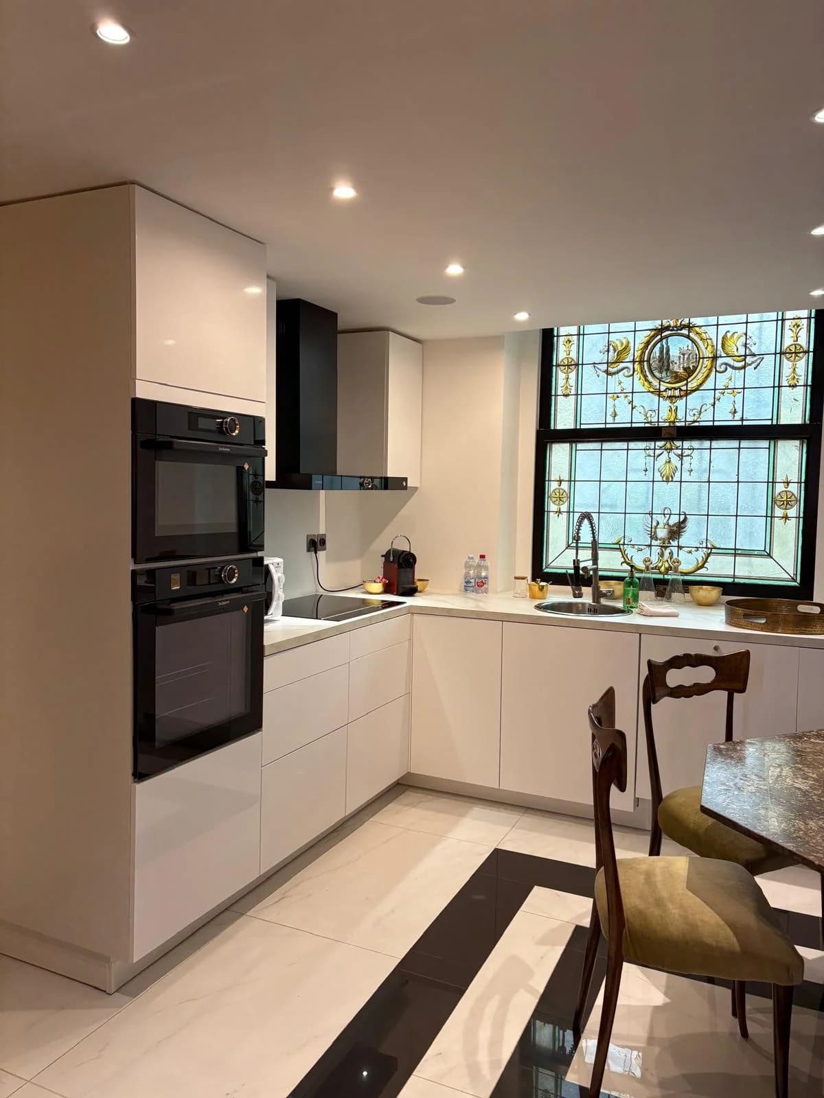 Modern white kitchen anchored by an Art Nouveau stained-glass window