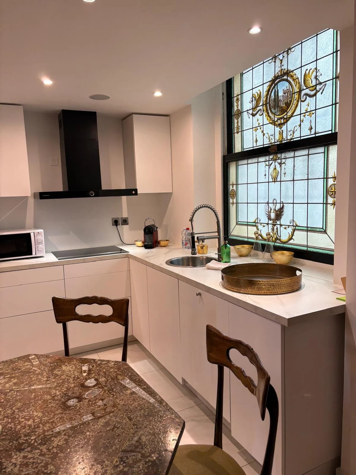 Kitchen detail with stained-glass illuminated above the sink and induction