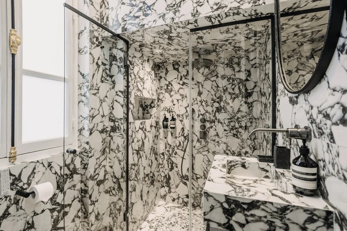 Veined marble shower and vanity with brass and black hardware