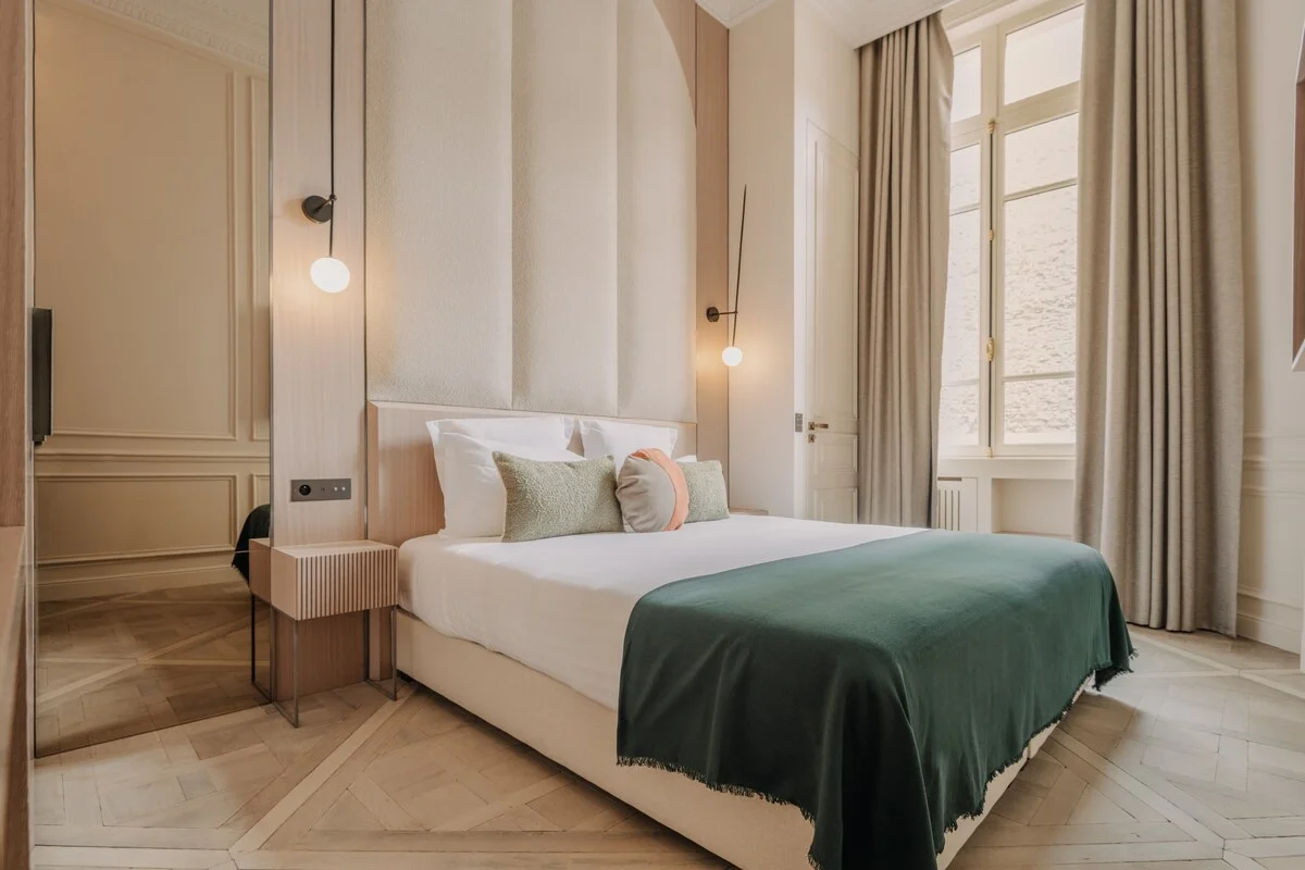 Primary bedroom with tall French windows, boucle headboard and emerald throw