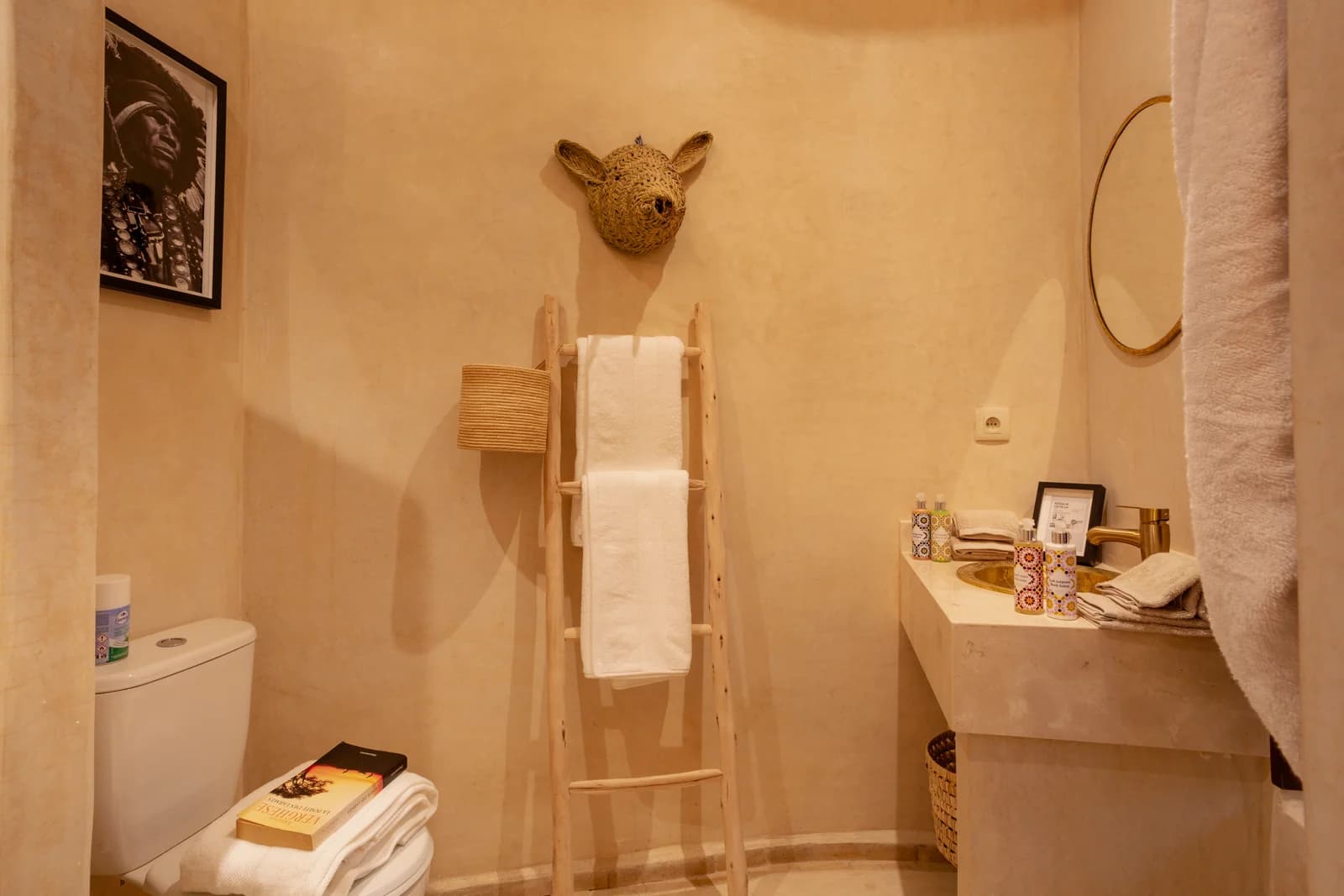 Tadelakt bathroom with stone sink, ladder towel rail and woven mask