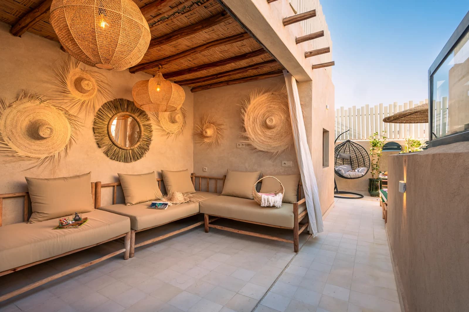 Rooftop lounge with linen sofas, woven sun mirrors and pergola shade