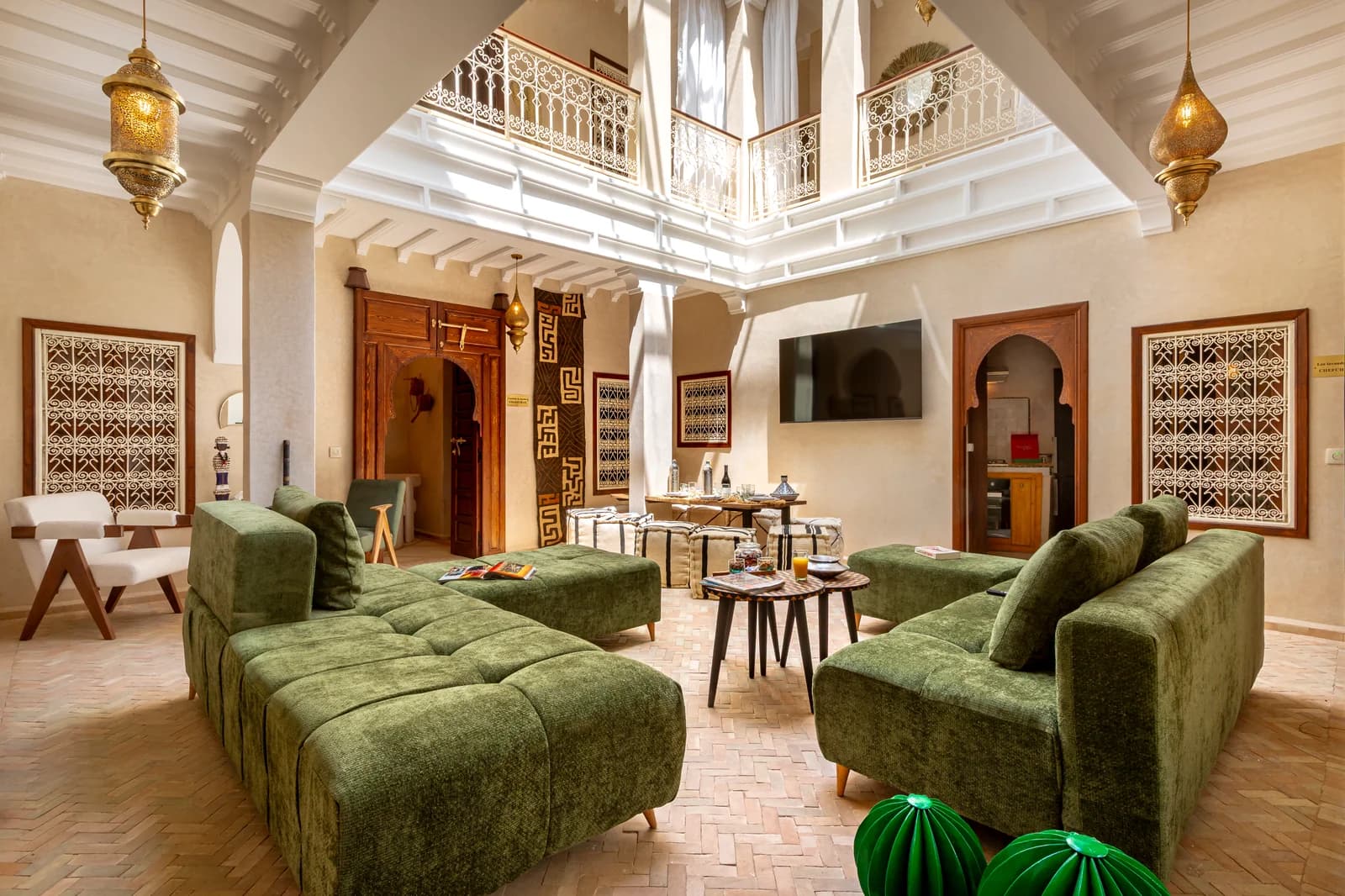 Wide living room with green velvet sofas under double-height atrium skylight