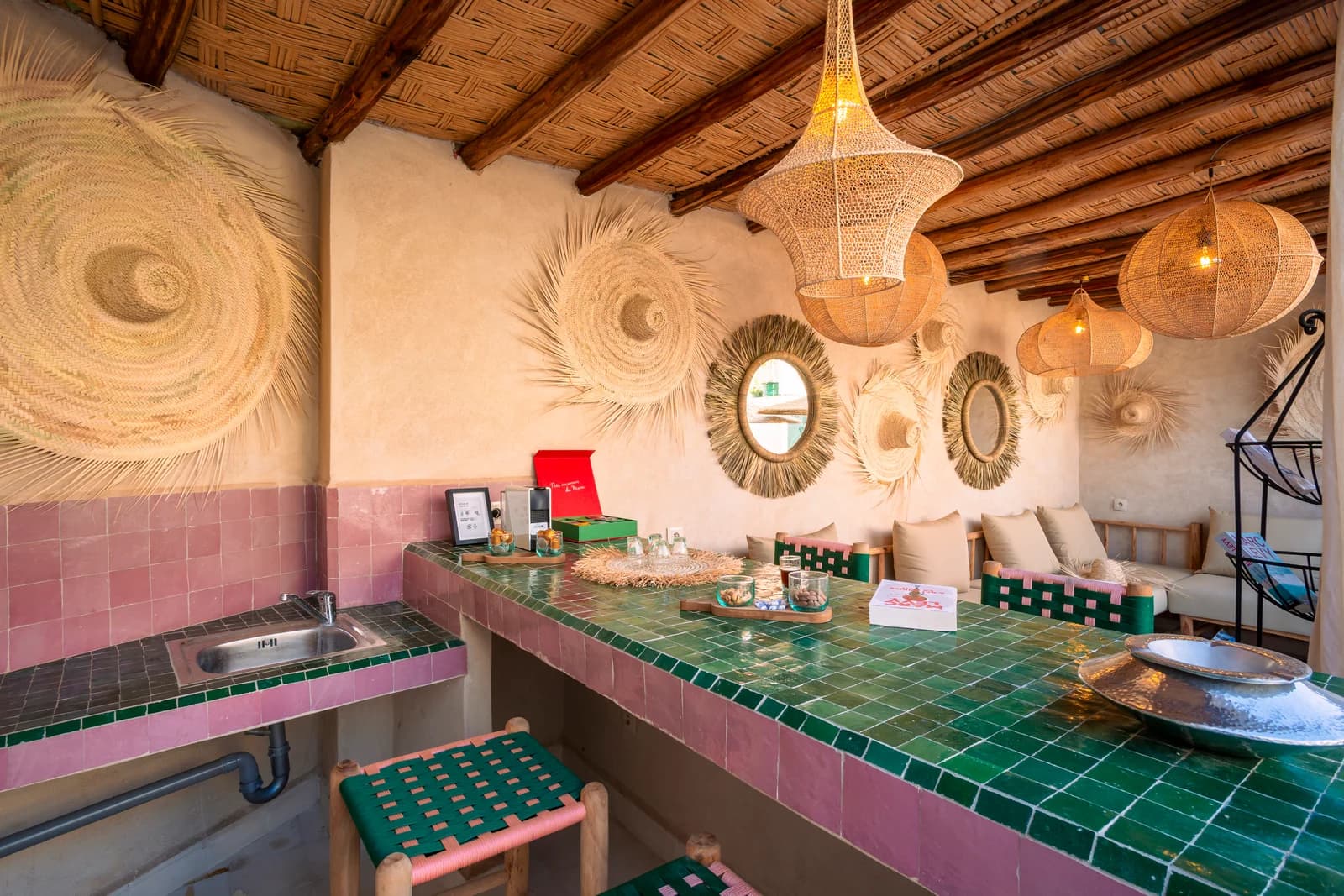 Rooftop kitchenette clad in emerald zellige tile with woven wall art