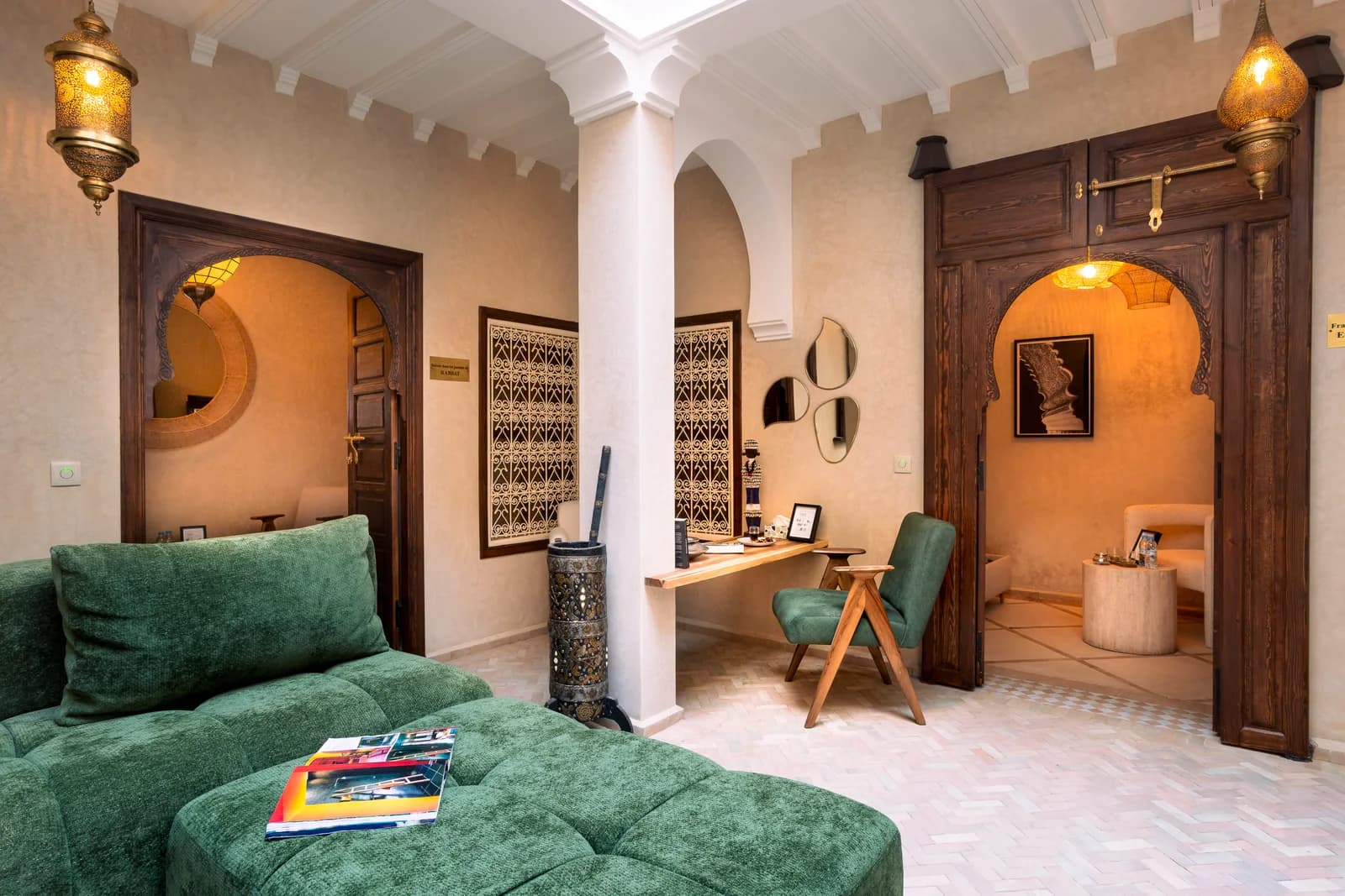 Green velvet sofa framed by carved arches and Moorish lantern detailing