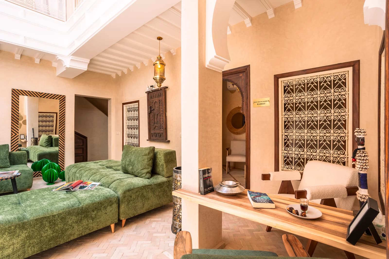Living lounge with tufted green sofa and console under riad atrium