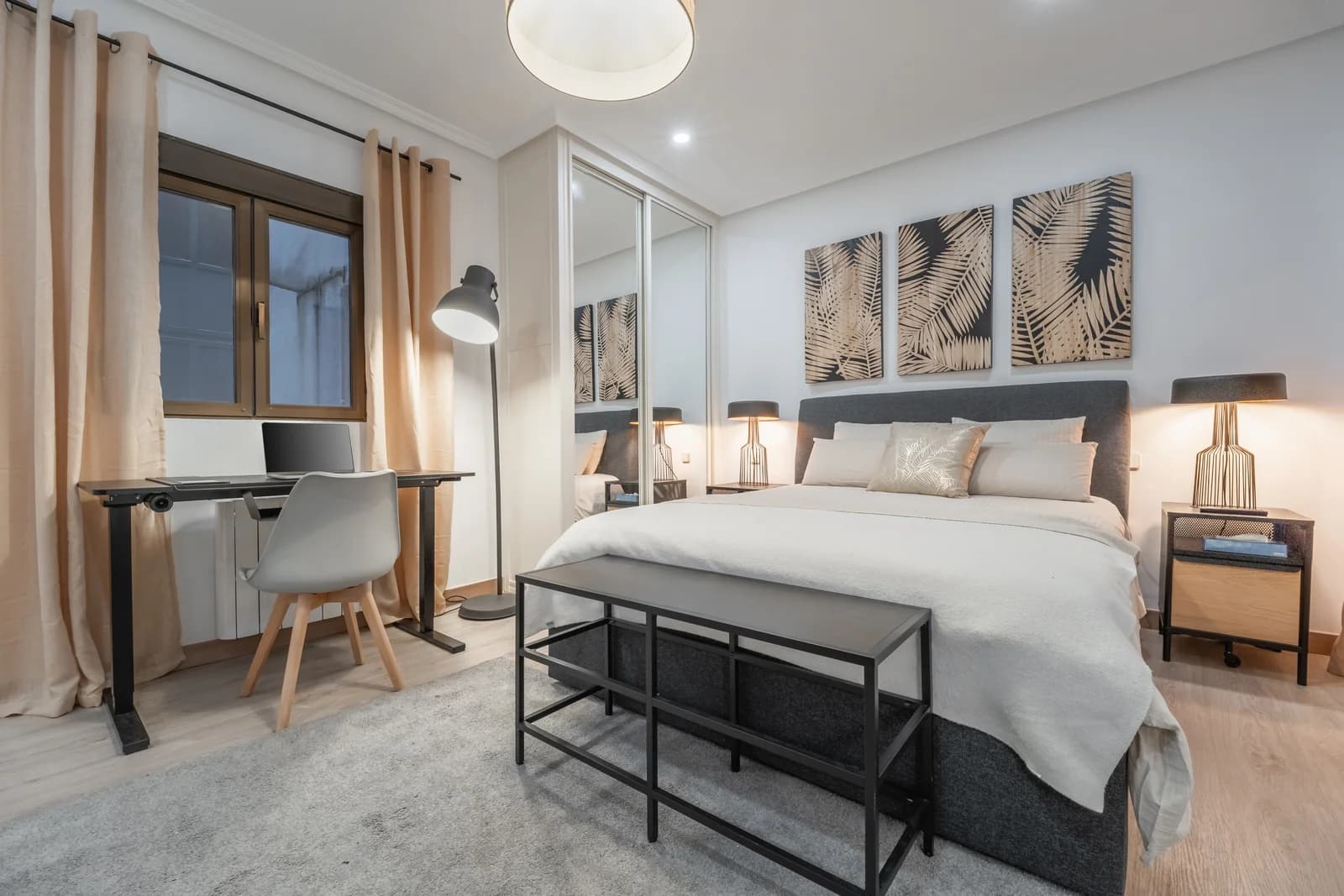 Master bedroom with king bed, palm-leaf art trio and bench at foot