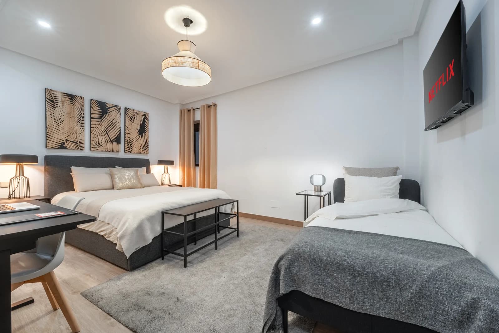 Family bedroom pairing a queen with extra single bed under woven pendant