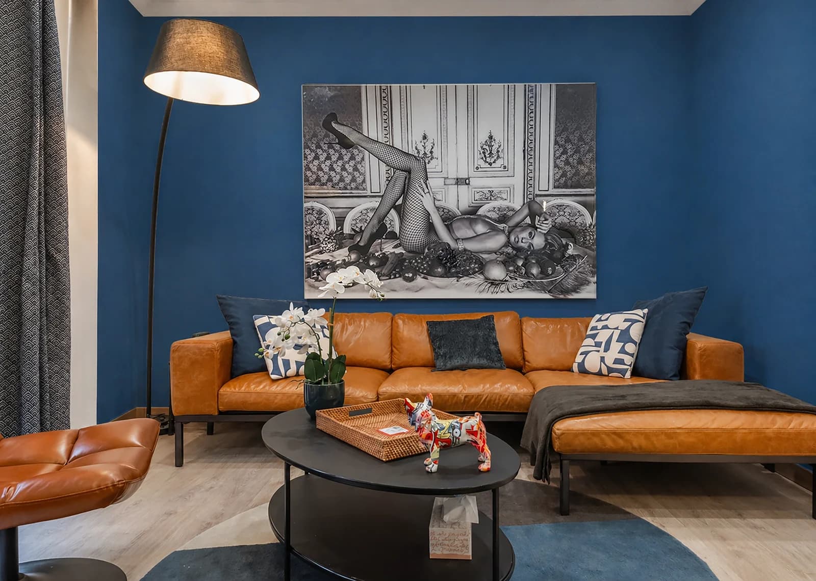 Tan leather sectional against deep blue accent wall with statement art