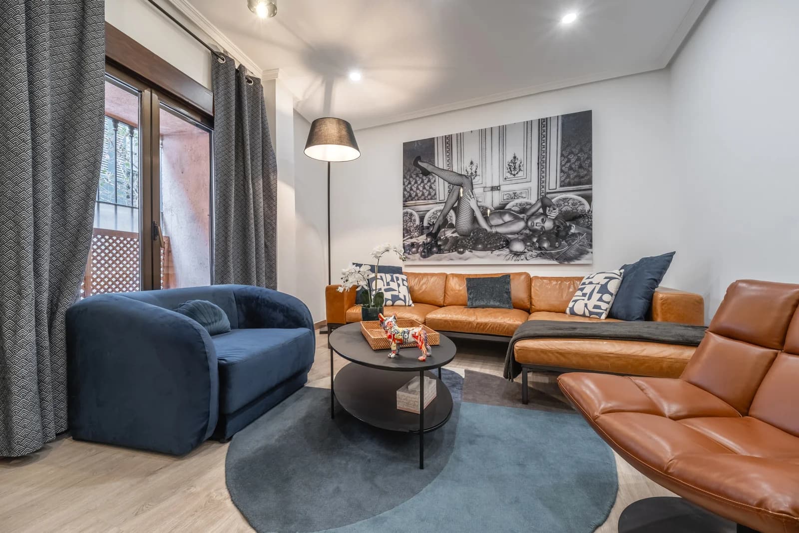 Living room with leather sectional, navy velvet armchair, and balcony light