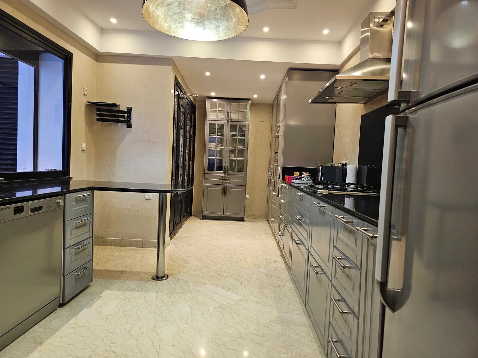 Galley kitchen in grey cabinetry with marble floors and stainless appliances