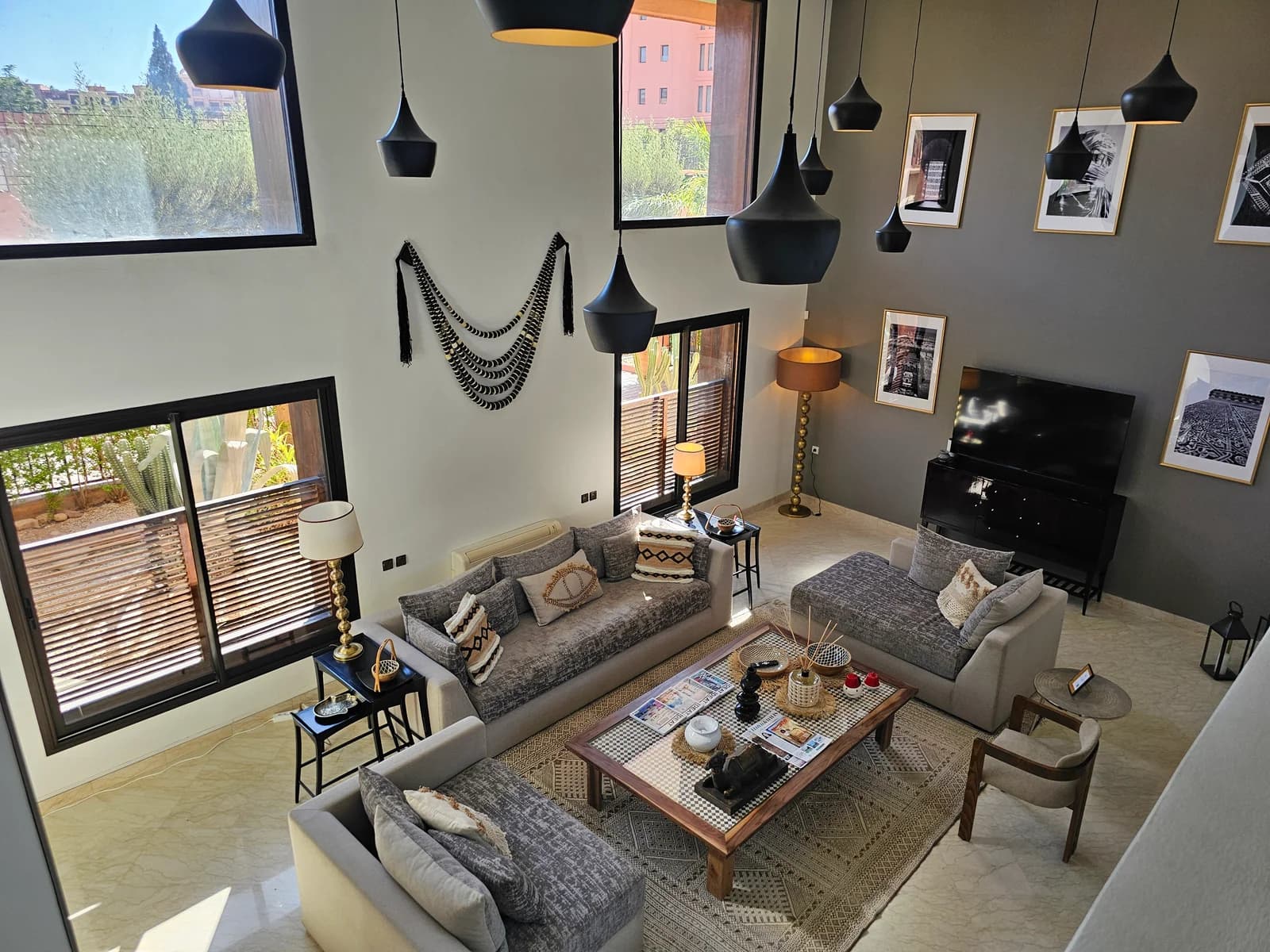 Elevated view of living showing tall windows and sculptural black pendants