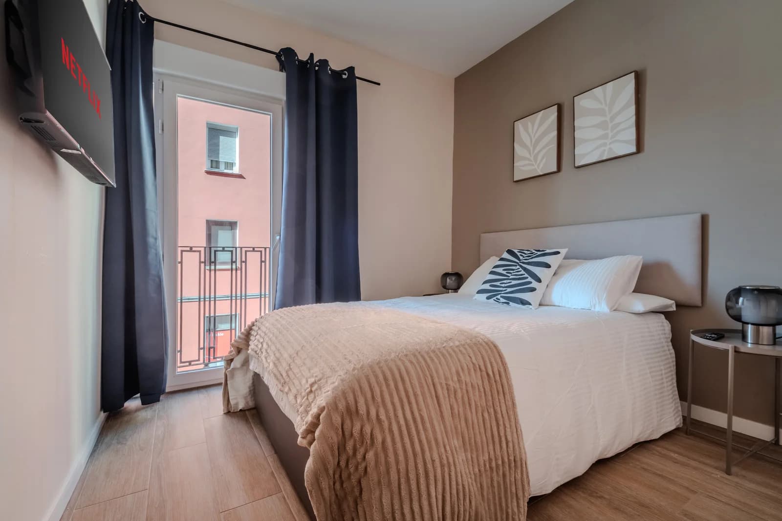 Bedroom with French balcony, taupe accent wall and botanical prints