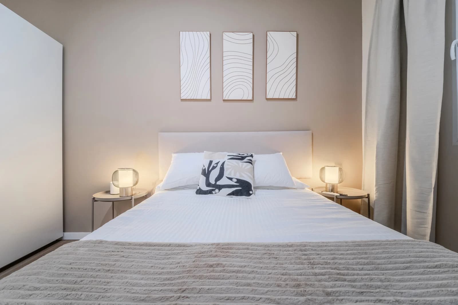 Calm bedroom with abstract triptych above headboard and matching nightstands