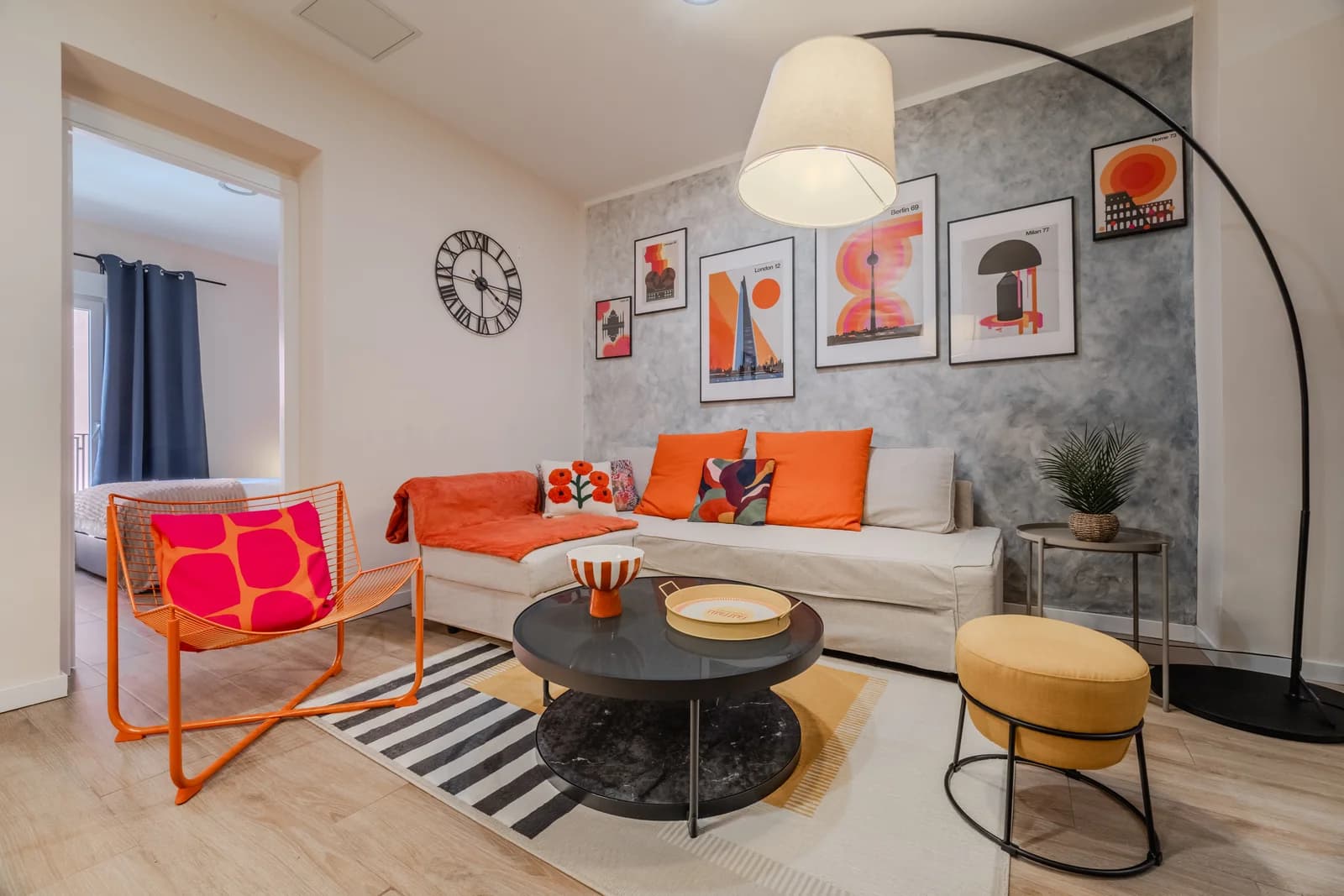 Wide living room with mid-century gallery wall, orange accents and arc floor lamp
