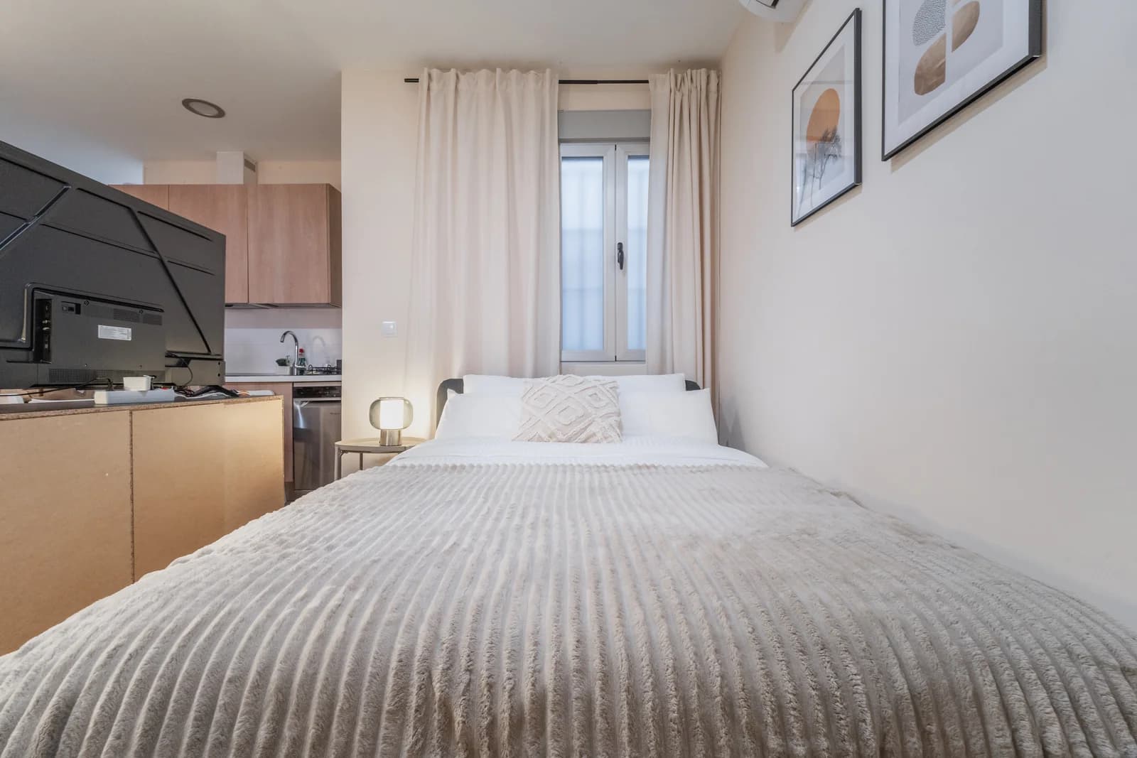 Studio layout with kitchenette behind bed and bright window light