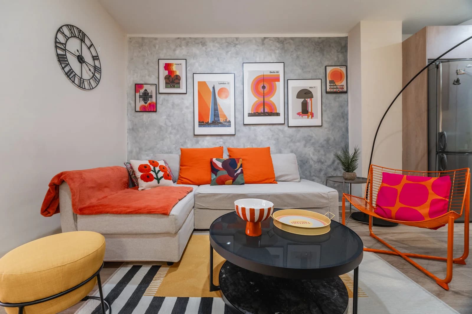 Sectional sofa under graphic pop-art prints with striped rug below