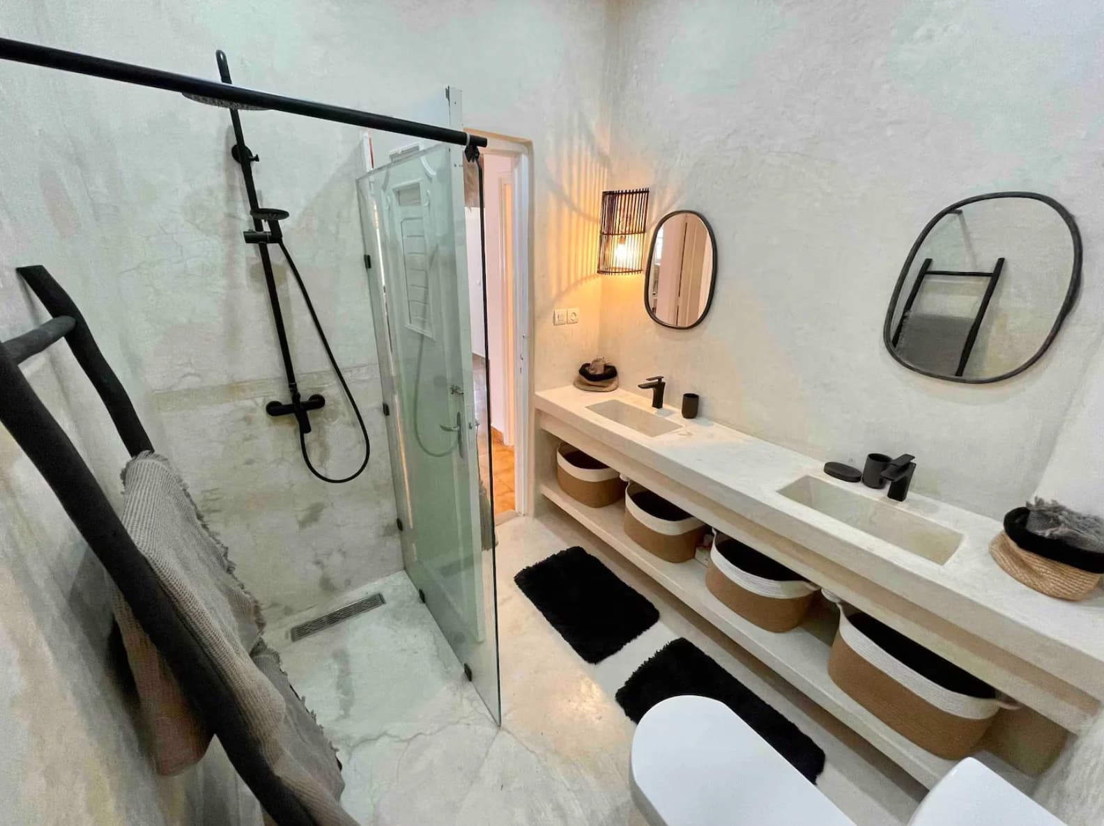 Limewash double-vanity bathroom with twin oval mirrors and rattan baskets