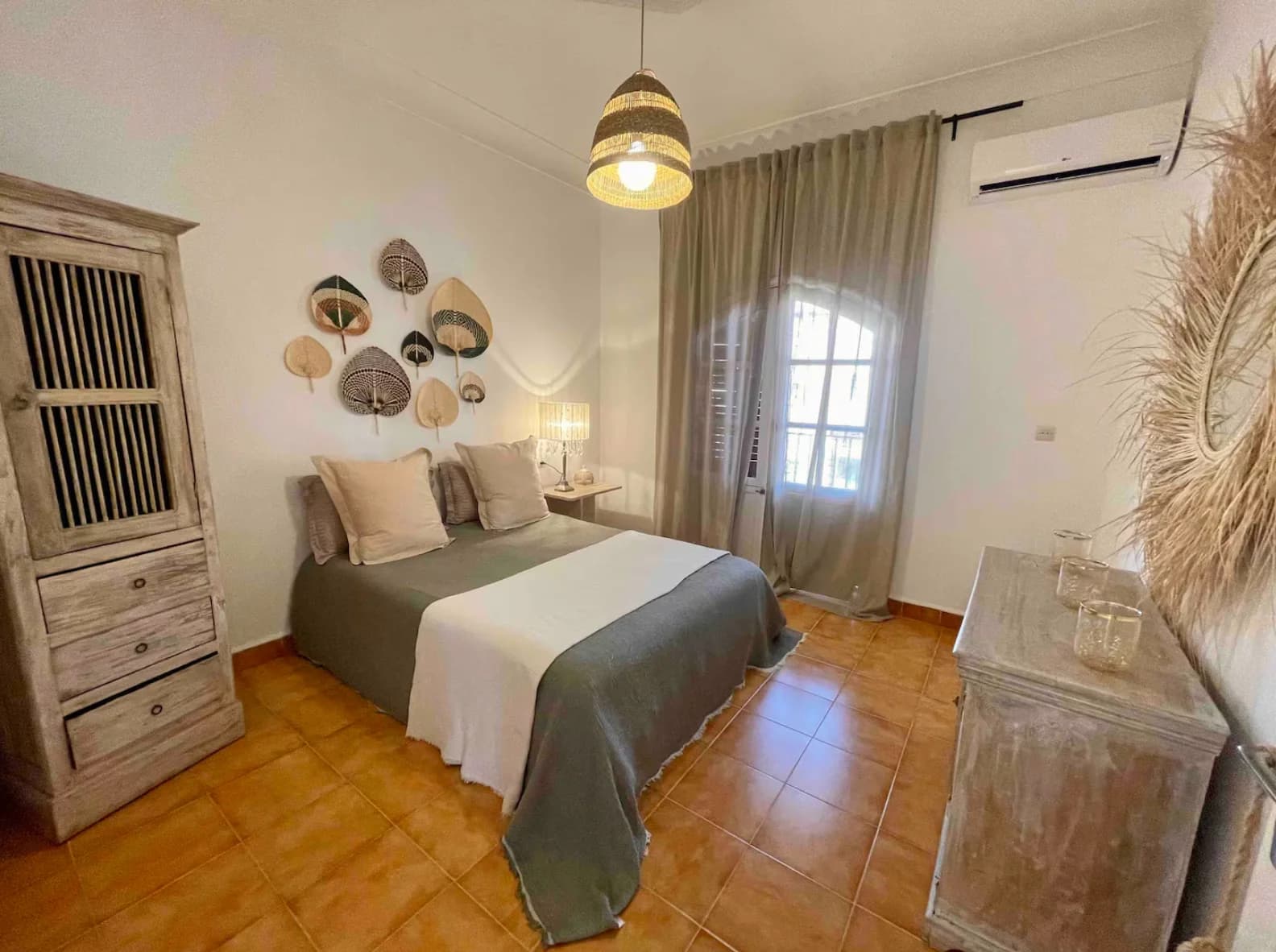 Bedroom with woven fan wall art and rattan pendant above bed