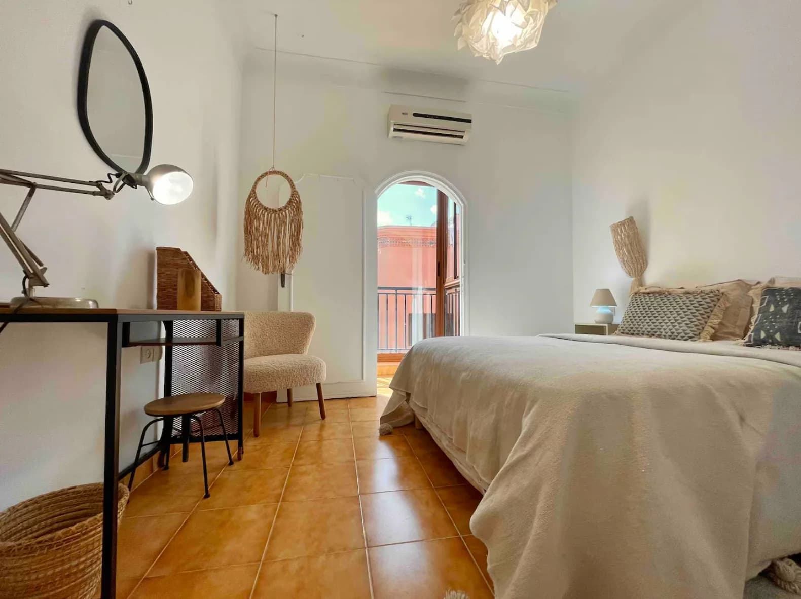 Airy bedroom with arched window, desk corner and balcony access