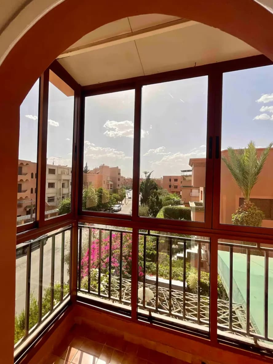 Arched balcony view over Marrakech rooftops and palm-lined boulevard