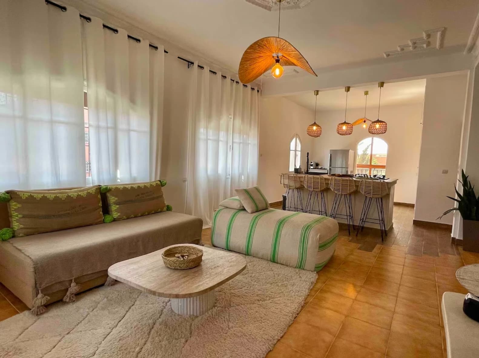 Wide bright living room with woven pendants opening onto kitchen