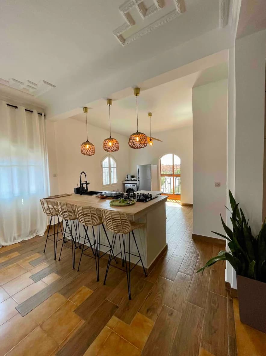 Compact island kitchen with stools beneath warm glass pendants