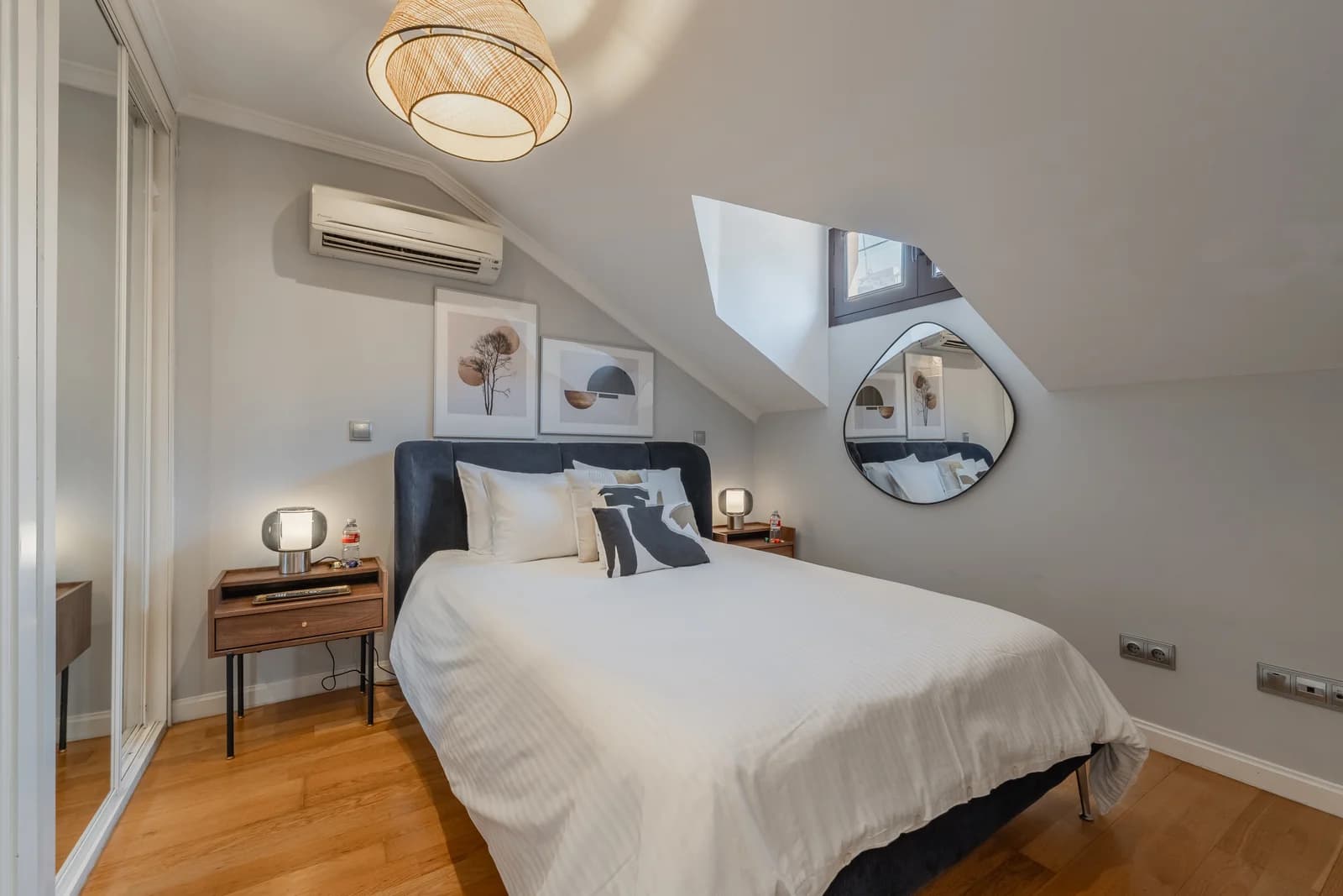 Skylit bedroom with botanical prints and asymmetric mirror