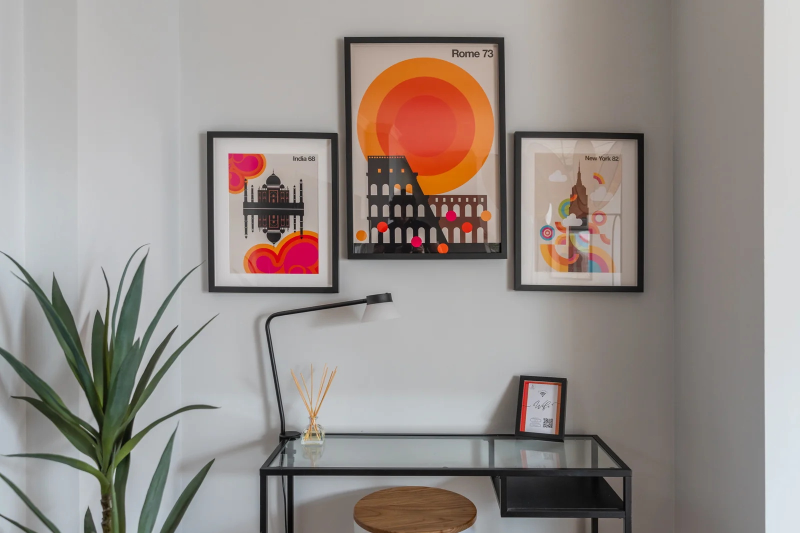 Vintage-inspired city poster gallery above glass writing desk