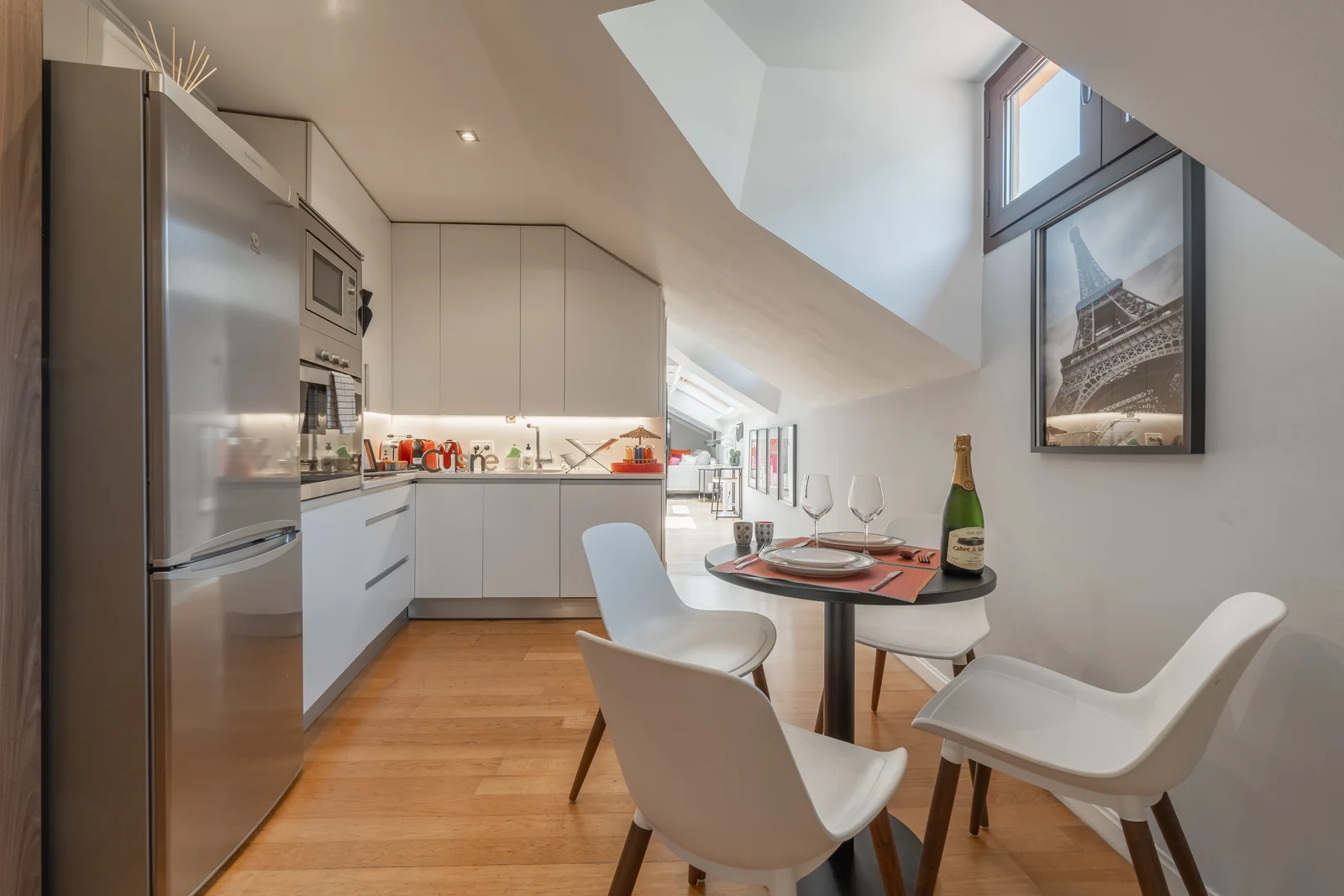 Sleek kitchen-diner with skylight and Eiffel Tower print artwork