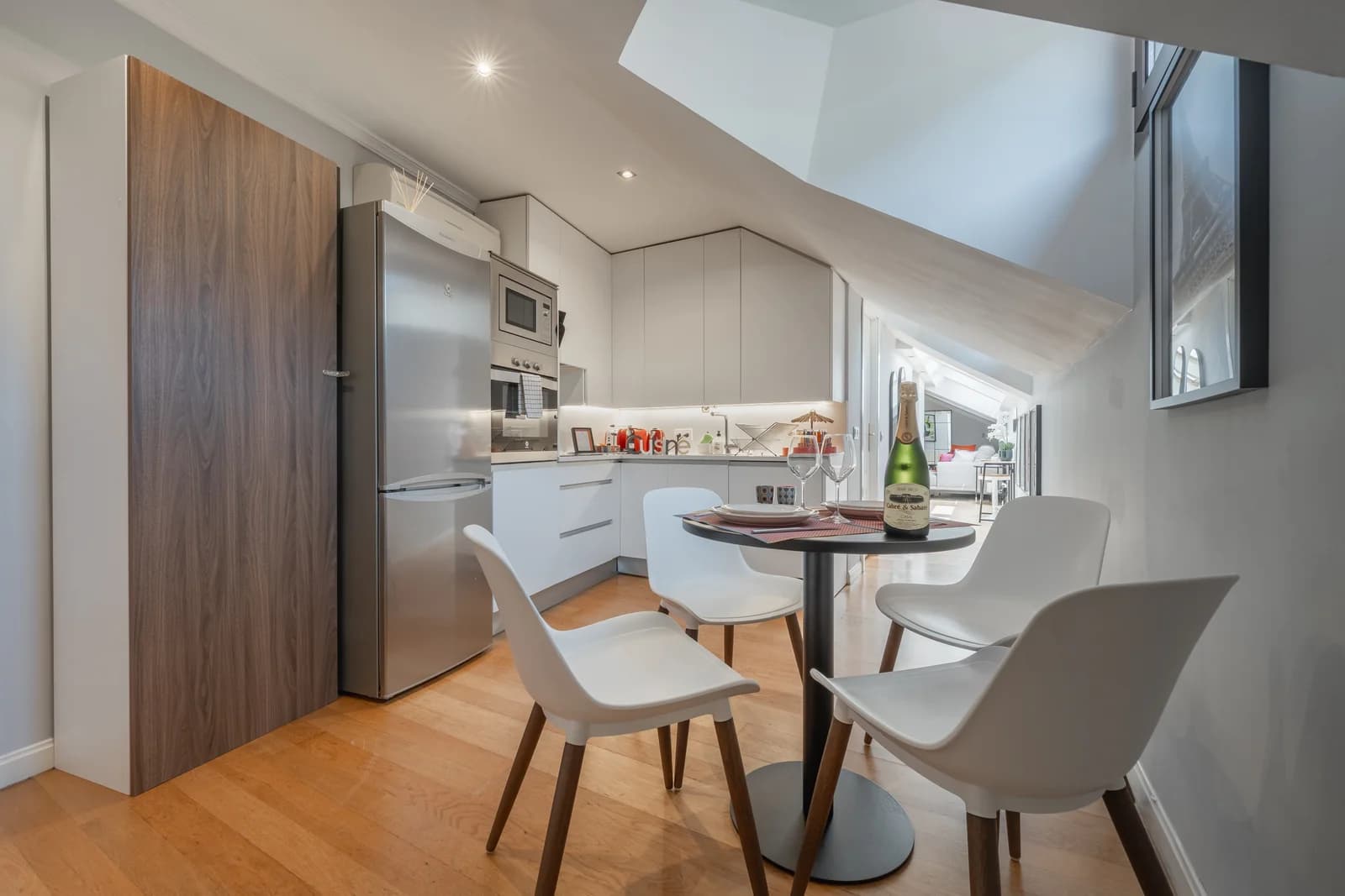 Modern white kitchen with walnut accents and round bistro table