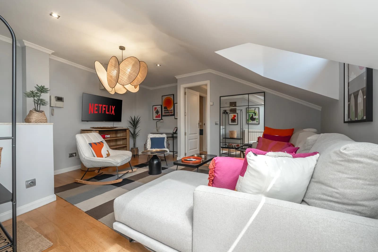Cosy attic living area with rocker, sectional sofa and TV wall