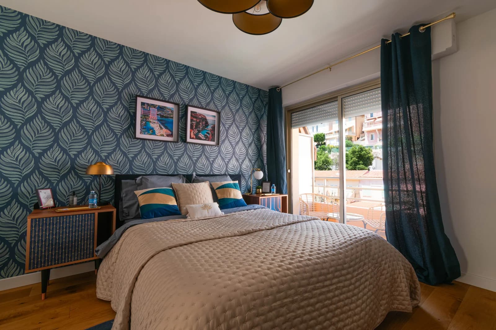 Teal palm wallpaper bedroom with gold pendant trio and balcony