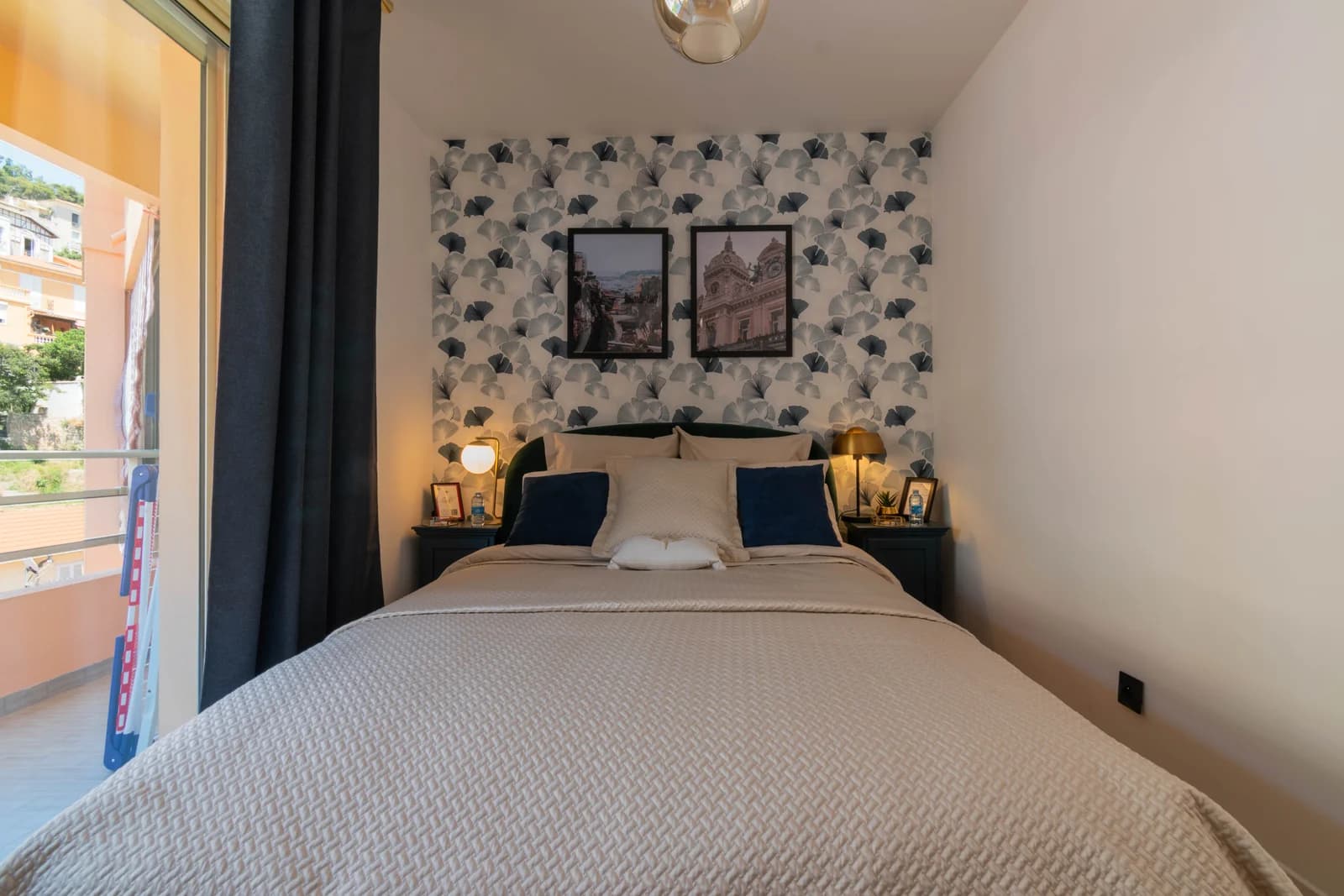 Compact guest bedroom with patterned wallpaper and balcony door