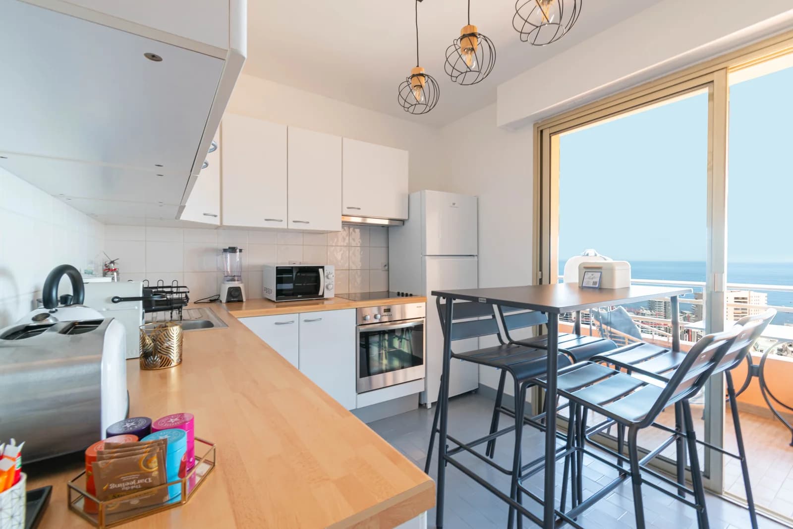 White kitchen with breakfast bar opening to sea-view balcony