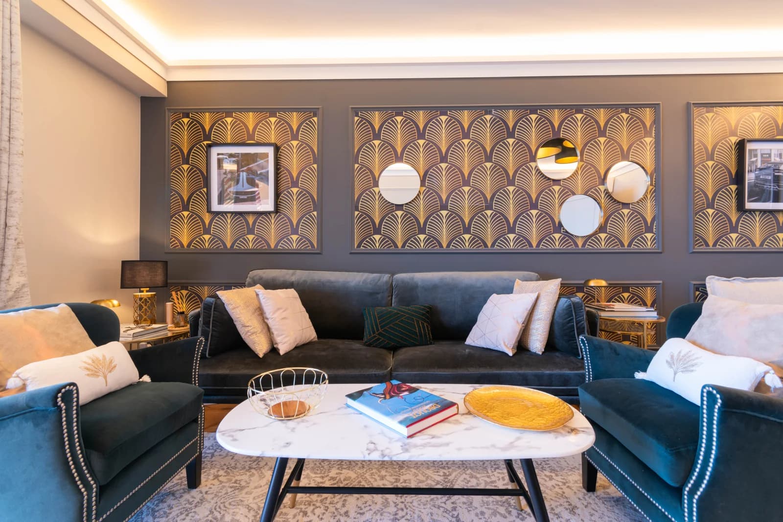 Velvet sofas and gold deco wallpaper centred on marble coffee table