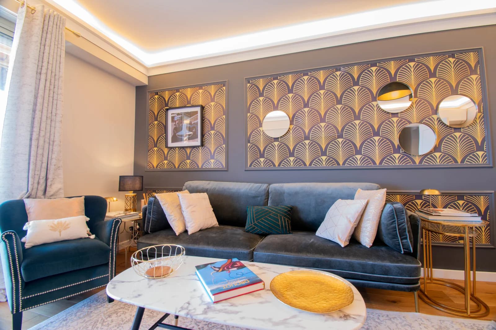 Navy velvet sofa against gold fan-pattern wall with marble table