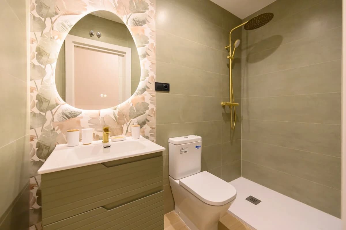 Sage tile bathroom with floral wallpaper and gold rain shower