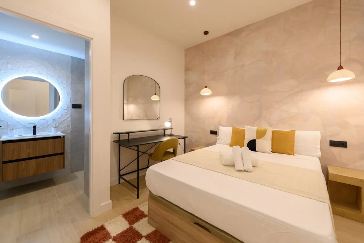 Master bedroom with plaster-finish walls and ensuite with backlit mirror