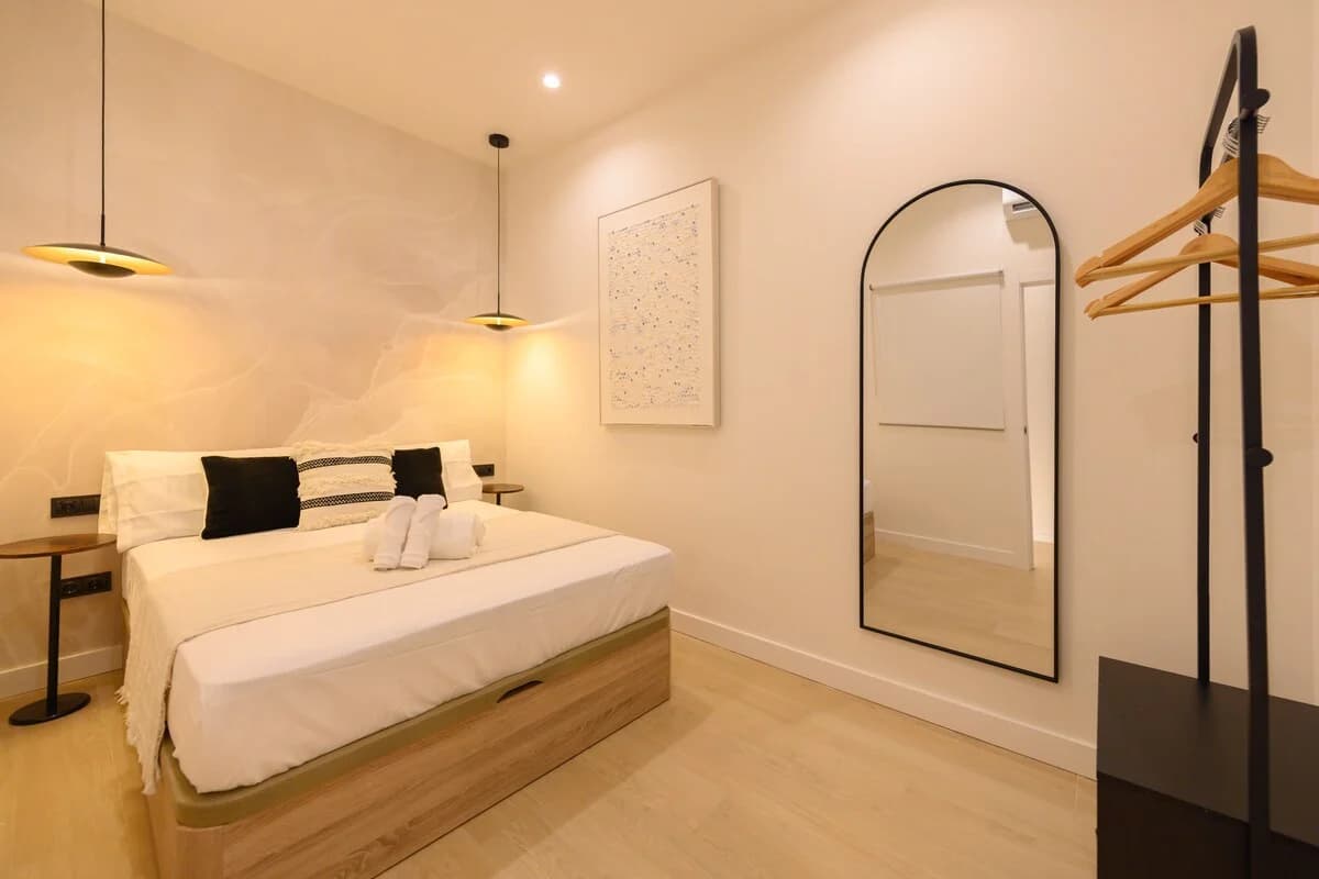 Minimal bedroom with arched mirror and saucer pendant lights
