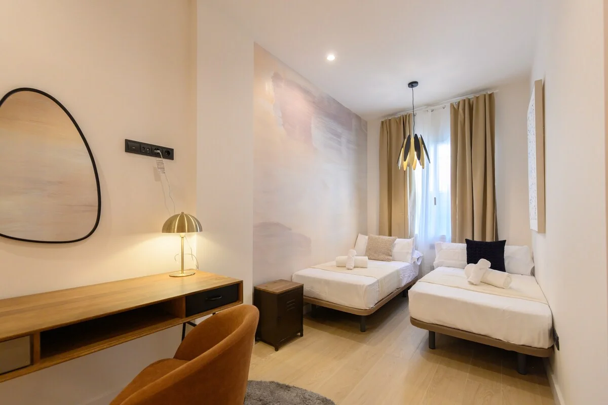Twin-bed room with painterly wall mural and brass desk lamp