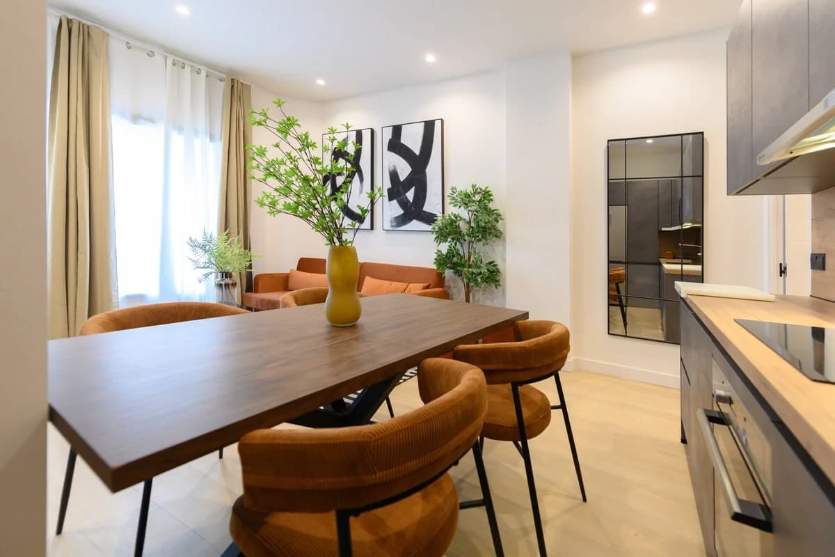 Walnut dining table with corduroy chairs framed by ribbed-glass partition